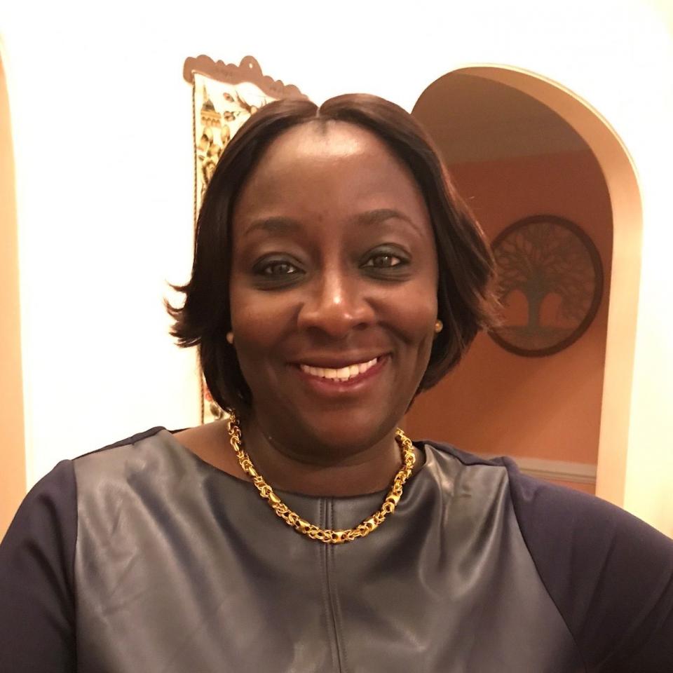 Portrait of a smiling dark-skinned woman with chin-length hair and a necklace